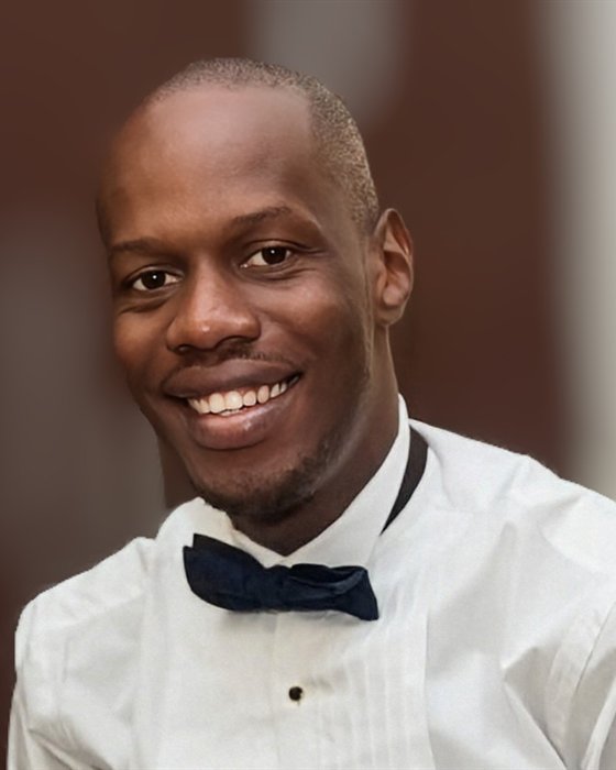 Portrait of Iyke Nnaemeka, smiling, in a white shirt and bow tie.